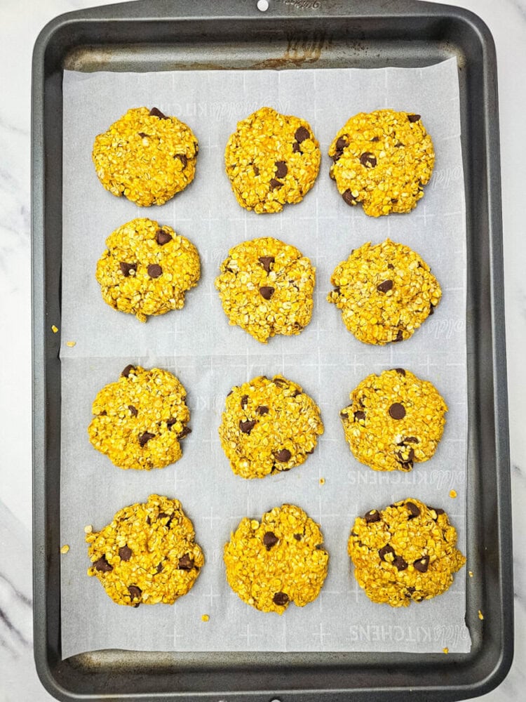 Twelve oatmeal chocolate chip cookies on a baking sheet lined with parchment paper.