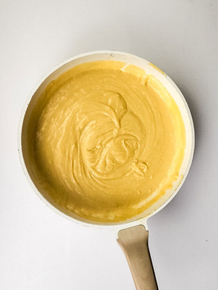 A white skillet filled with smooth, thick yellow batter sits on a white surface.