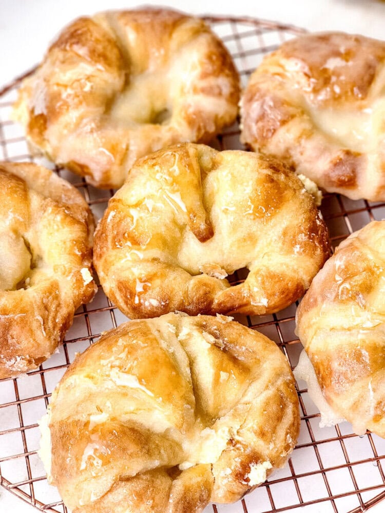 Six golden brown pastries with a flaky texture are arranged on a wire cooling rack.