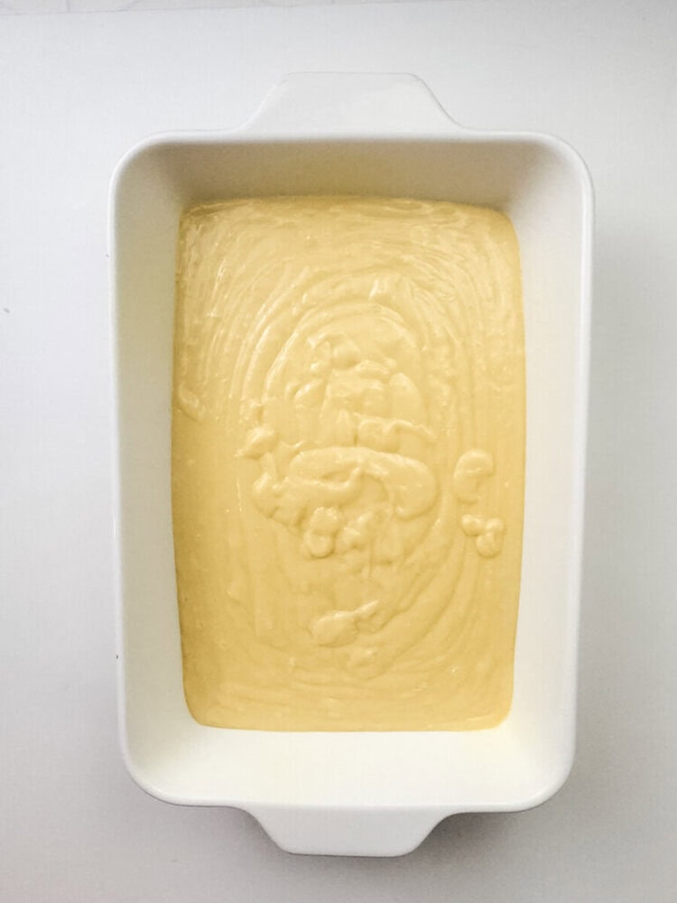 A white rectangular baking dish filled with an even layer of yellow cake batter, ready to be baked.