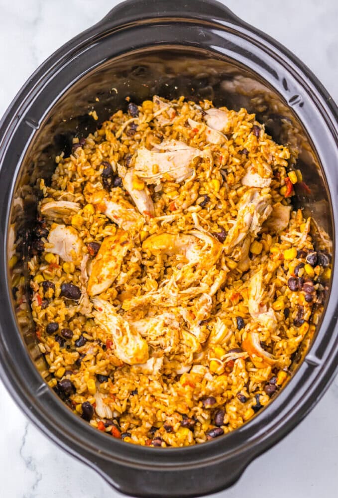Shredded chicken, rice, black beans, and corn mixed together in a slow cooker.