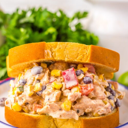 A chicken salad sandwich on thick sliced bread, filled with a mixture of chicken, black beans, corn, red bell pepper, and creamy dressing.
