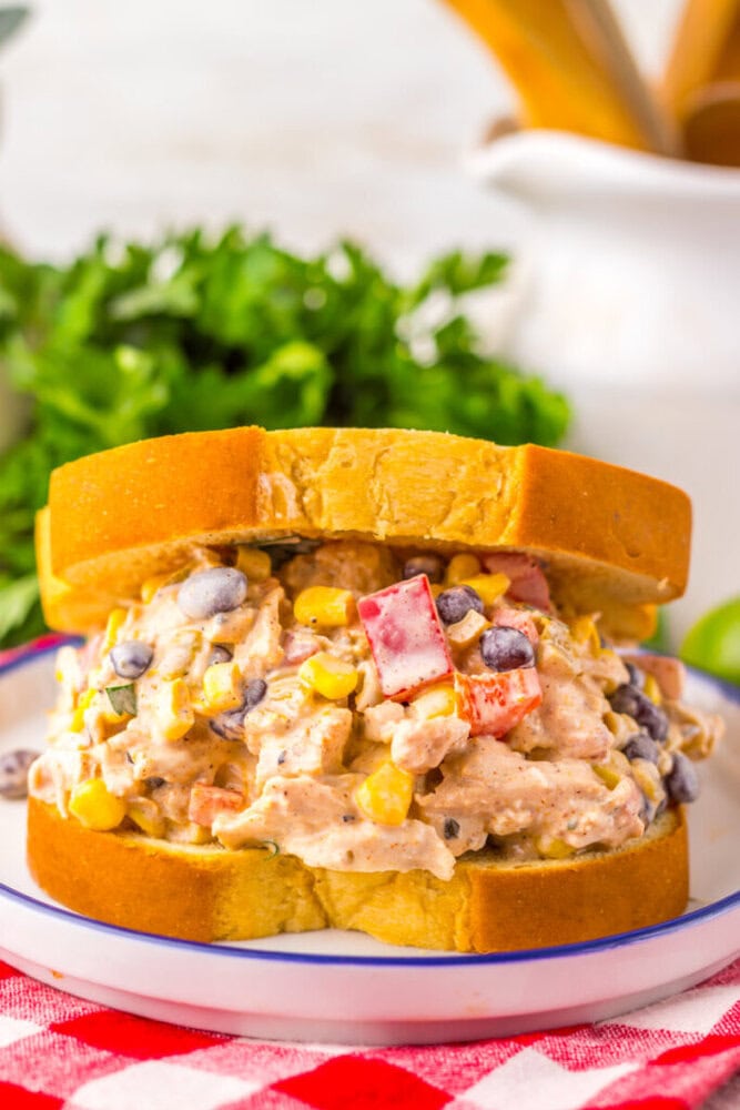 A chicken salad sandwich on thick sliced bread, filled with a mixture of chicken, black beans, corn, red bell pepper, and creamy dressing.