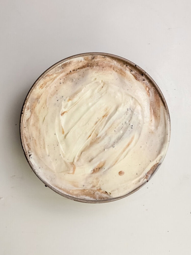 A round dish filled with a smooth, creamy mixture that appears to be swirled with light brown and white colors, set against a plain white background.