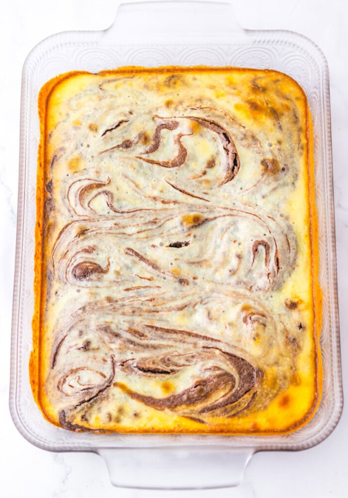 A glass baking dish filled with a baked casserole featuring swirled patterns of chocolate and cream-colored layers on top.