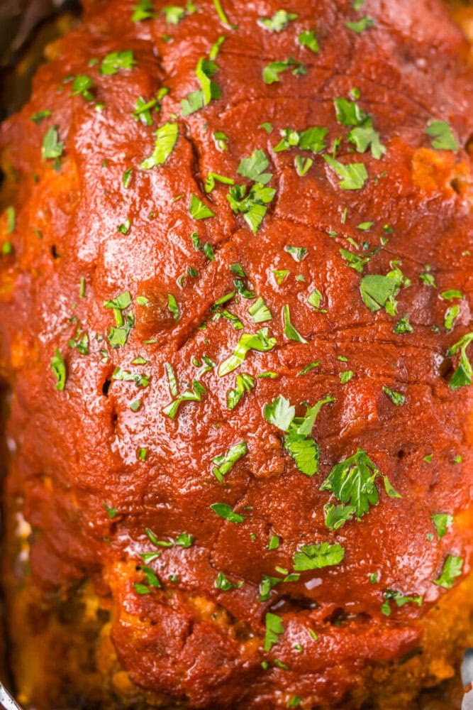 Close-up of a glazed meatloaf topped with chopped fresh parsley.