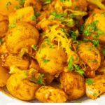 A plate of Sheet Pan Mississippi Chicken and Potatoes topped with melted cheese and chopped parsley.