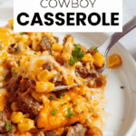 A plate of cheesy cowboy casserole with ground beef, corn, and beans, being scooped with a fork. Text overlay reads "Slow Cooker Cowboy Casserole.
