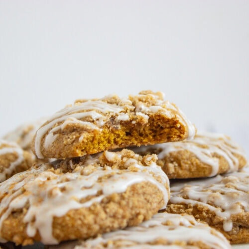 A stack of iced cookies with one cookie on top missing a bite, showing the soft texture inside.