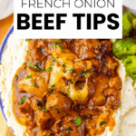 A bowl of mashed potatoes topped with slow-cooked beef tips in French onion sauce, garnished with melted cheese and chopped parsley, served with green vegetables.