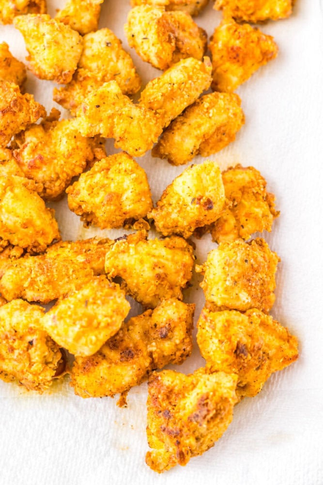 Golden brown pieces of breaded and fried chicken resting on a white paper towel.