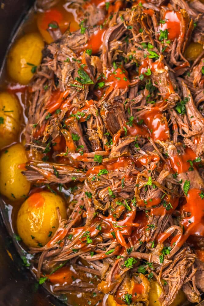 Shredded pot roast with baby potatoes, topped with fresh herbs and drizzled with red sauce.