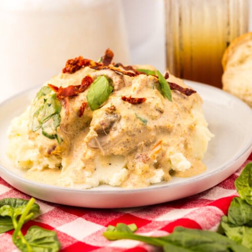 Creamy chicken with spinach and sun-dried tomatoes on mashed potatoes, served with bread and iced tea.