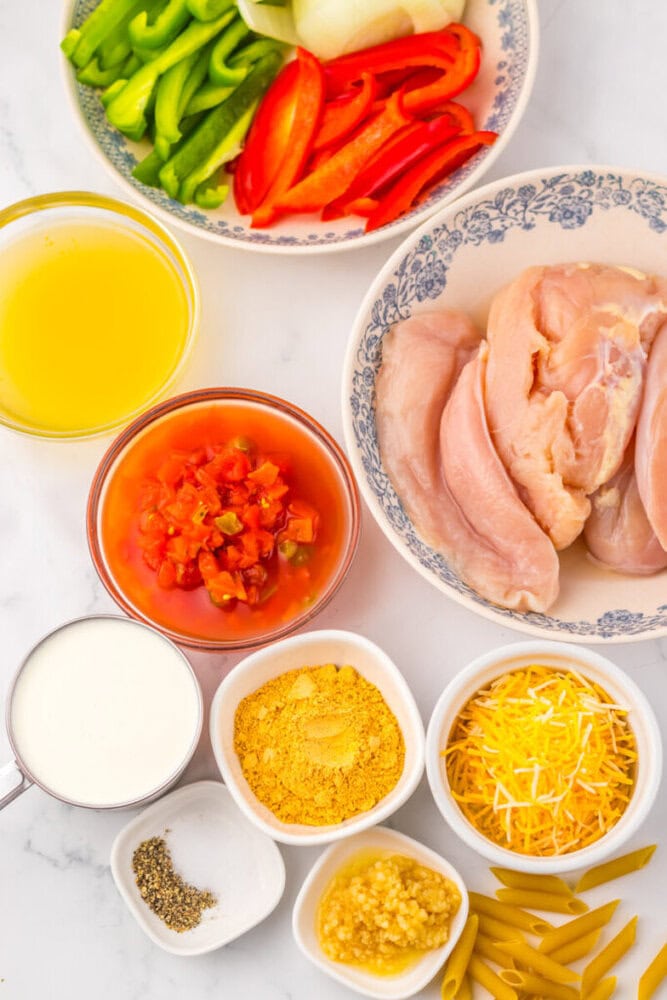 Raw chicken breasts, sliced bell peppers, onions, cheese, cream, pasta, broth, diced tomatoes, garlic, and spices.