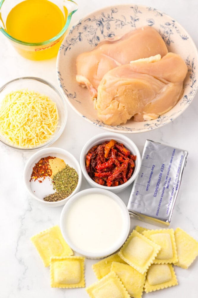 Ingredients for a recipe: chicken breasts, ravioli, broth, cheese, cream, spices, sun-dried tomatoes, and cream cheese.