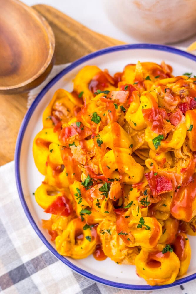 Slow cooker cheesy BBQ bacon chicken tortellini plated and garnished with fresh herbs