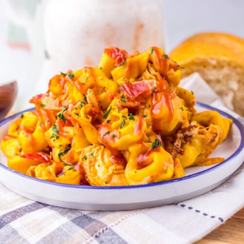 Slow cooker cheesy BBQ bacon chicken tortellini plated and ready to serve with fresh herb garnish