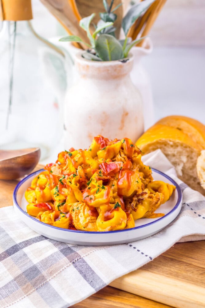 Slow cooker cheesy BBQ bacon chicken tortellini plated and garnished with herbs, ready to serve