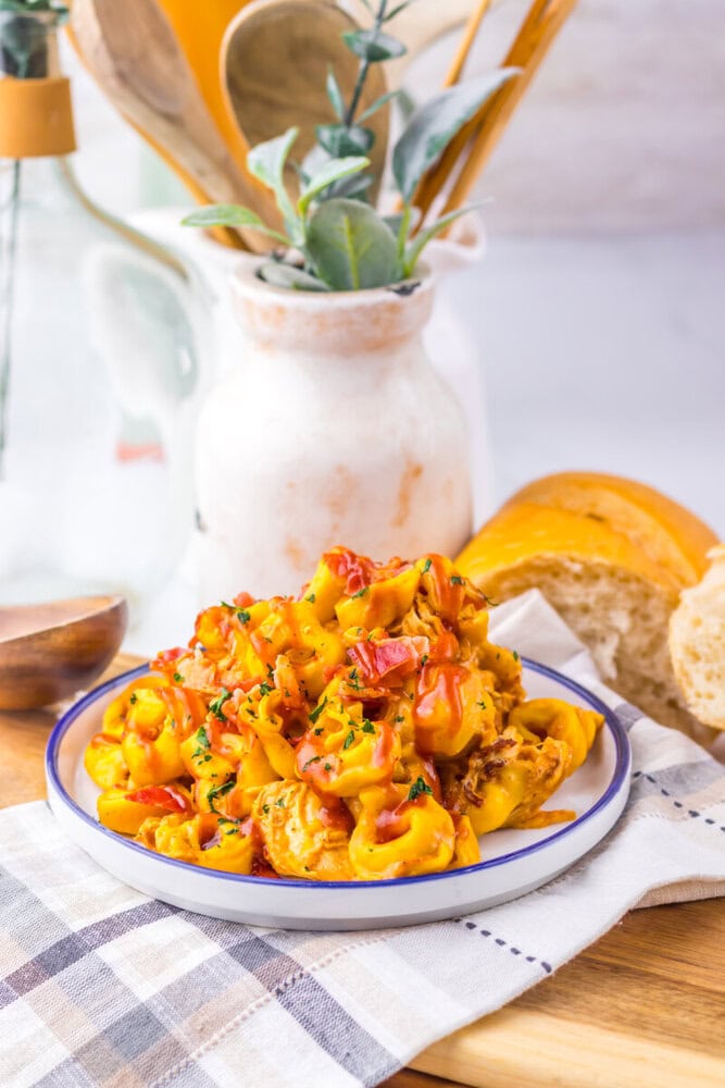 Slow cooker cheesy BBQ bacon chicken tortellini plated and garnished with peppers and herbs