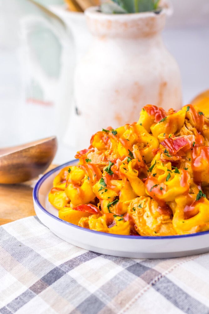 Slow cooker cheesy BBQ bacon chicken tortellini plated and garnished with fresh herbs