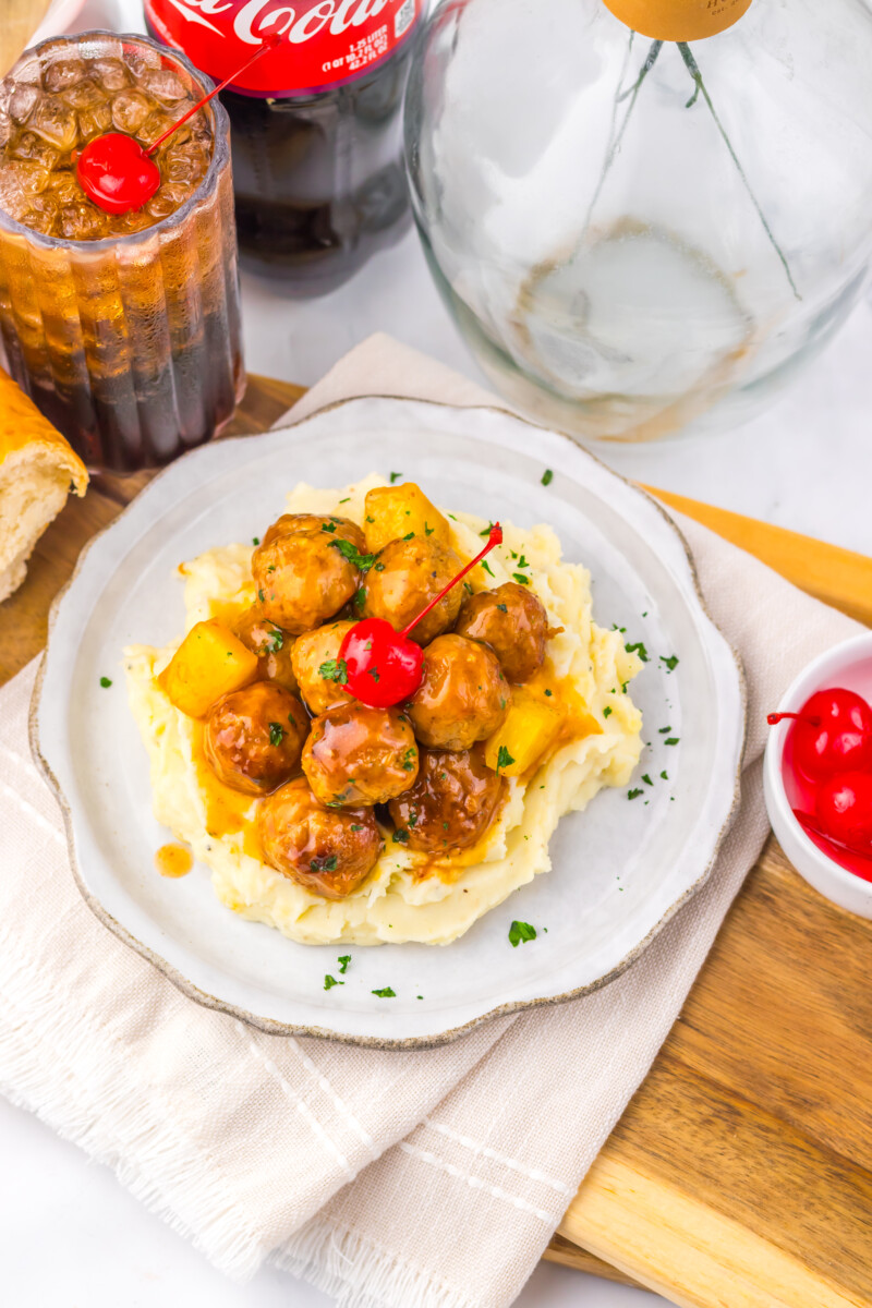 Slow cooker cherry cola pineapple BBQ meatballs served on mashed potatoes with pineapple and peppers