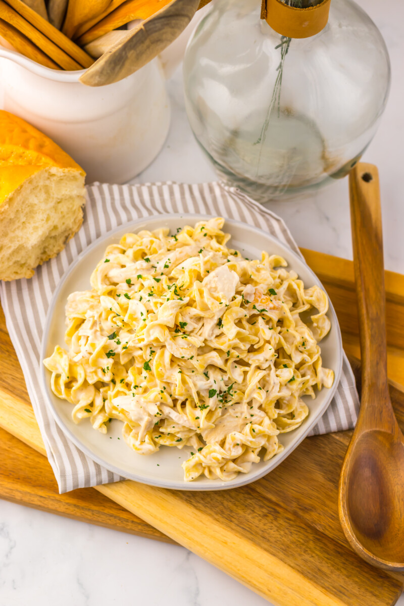 Slow cooker creamy garlic chicken and noodles plated on white dish with herb garnish
