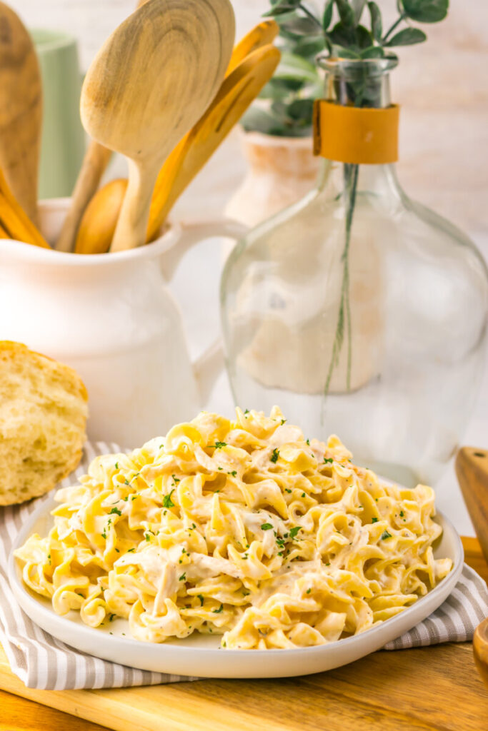 Creamy garlic chicken and noodles served on a white plate with fresh herb garnish