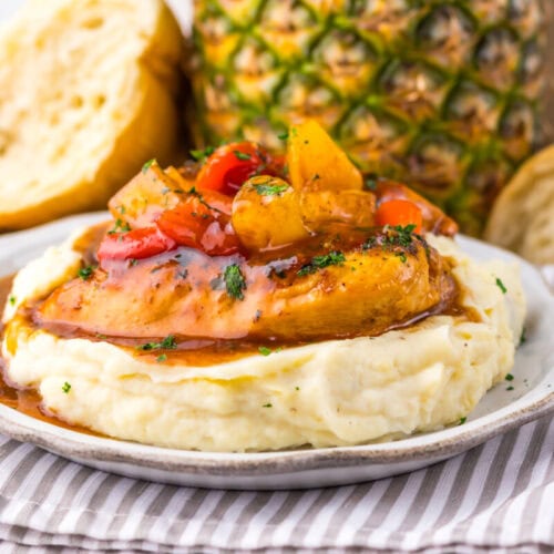 Slow cooker sweet chili pineapple chicken served over mashed potatoes with caramelized pineapple chunks and red pepper garnish
