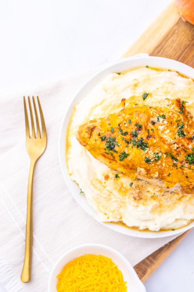 Sour cream and onion chicken breast with herb garnish served over creamy mashed potatoes
