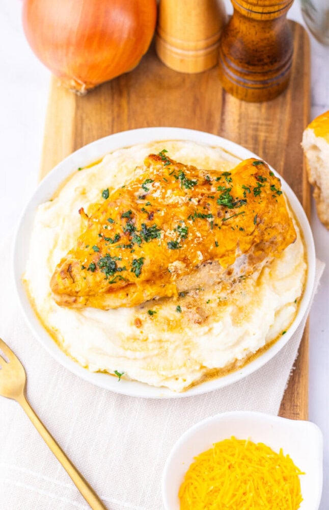 Sour cream and onion chicken breast on mashed potatoes garnished with fresh herbs