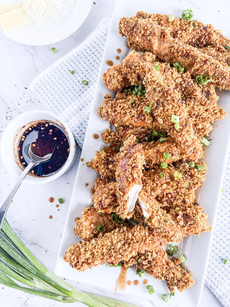 Crunchy baked chicken tenders with chili honey dipping sauce and green onion garnish