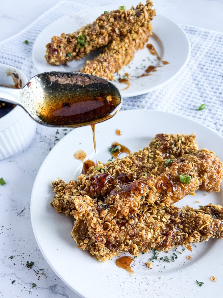 Crunchy baked chicken tenders with chili infused honey drizzle and herb garnish