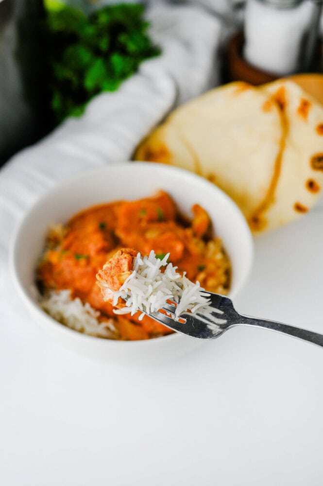 Slow Cooker Chicken Tikka Masala plated with rice and naan bread, fork with rice in foreground