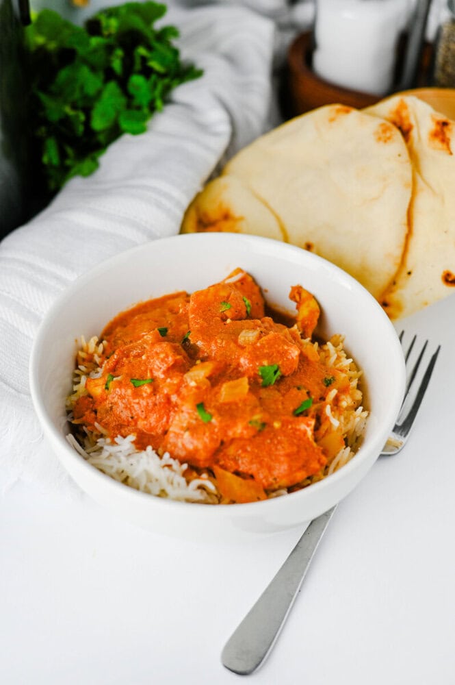 Slow Cooker Chicken Tikka Masala plated in white bowl with rice and naan bread