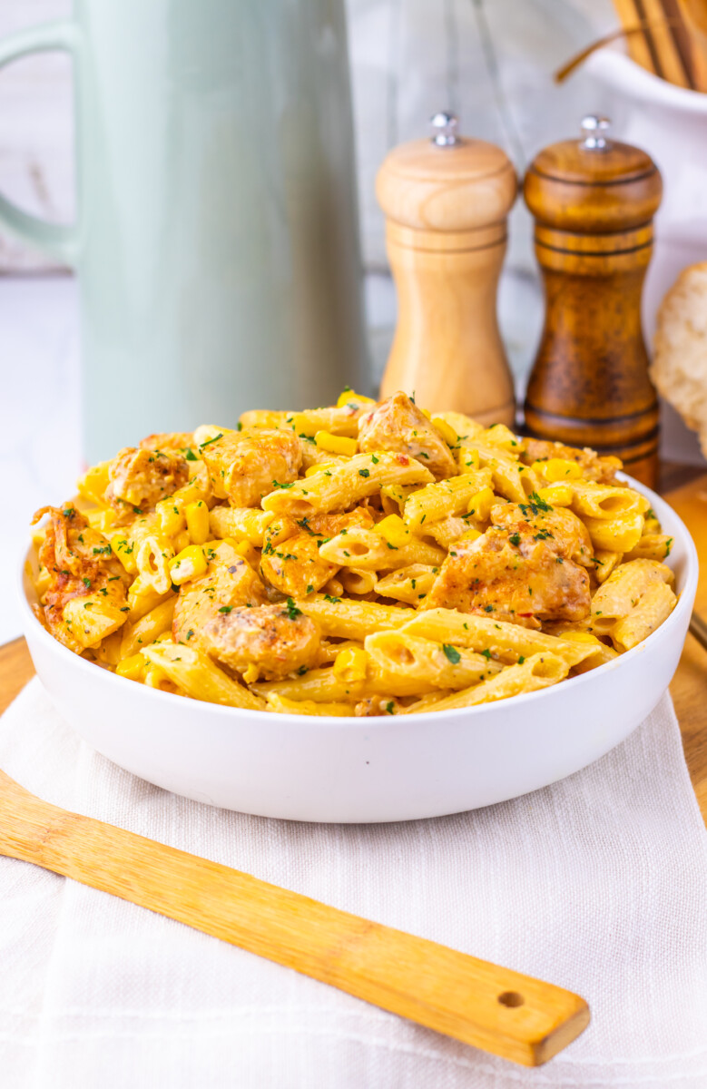 Creamy Cajun corn chicken pasta in white bowl with herbs garnish, ready to serve