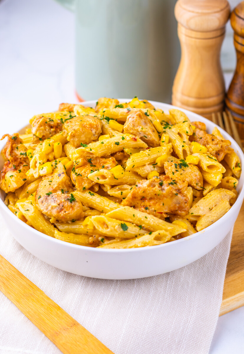 Creamy Cajun corn chicken pasta in white bowl with fresh herb garnish