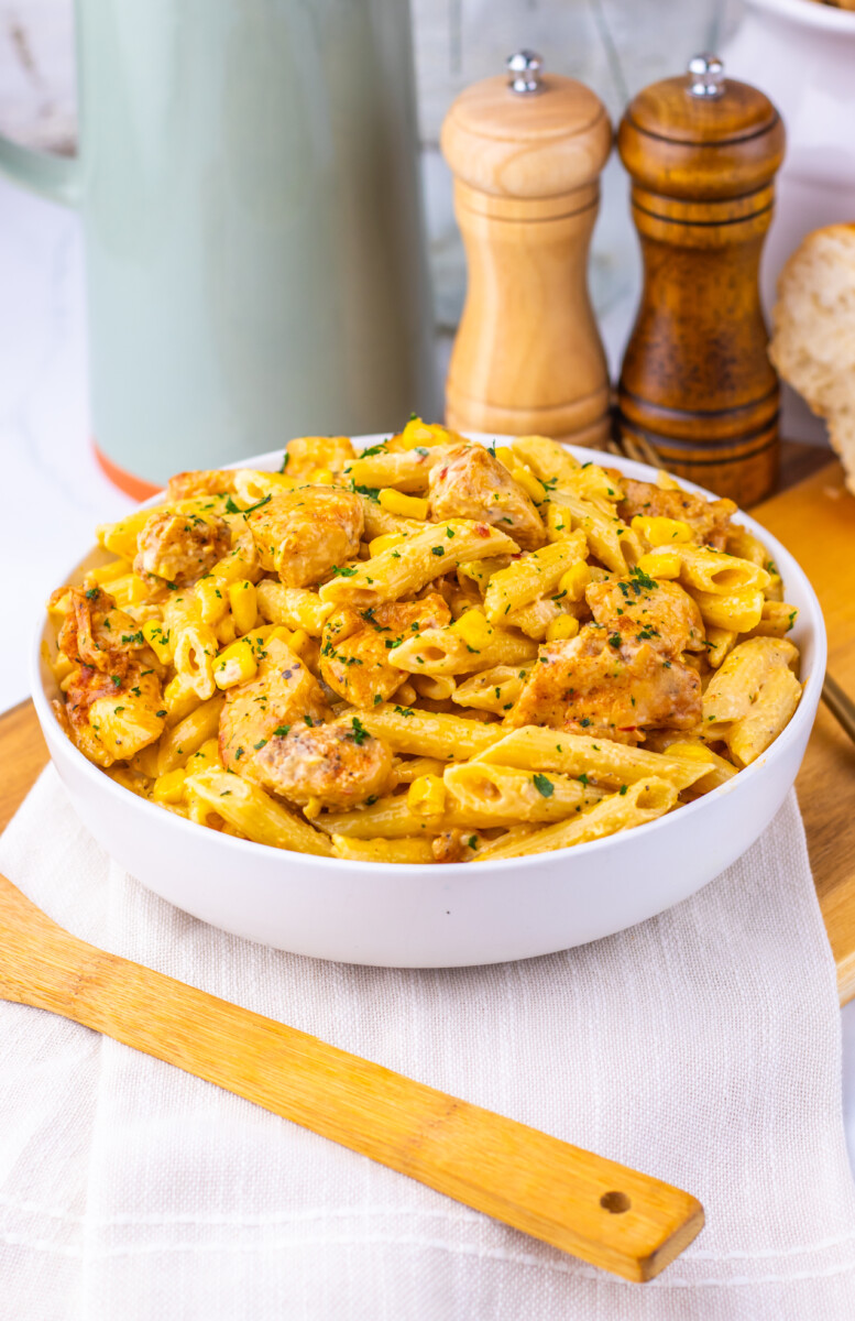 Creamy Cajun Corn Chicken Pasta served in white bowl with fresh herb garnish