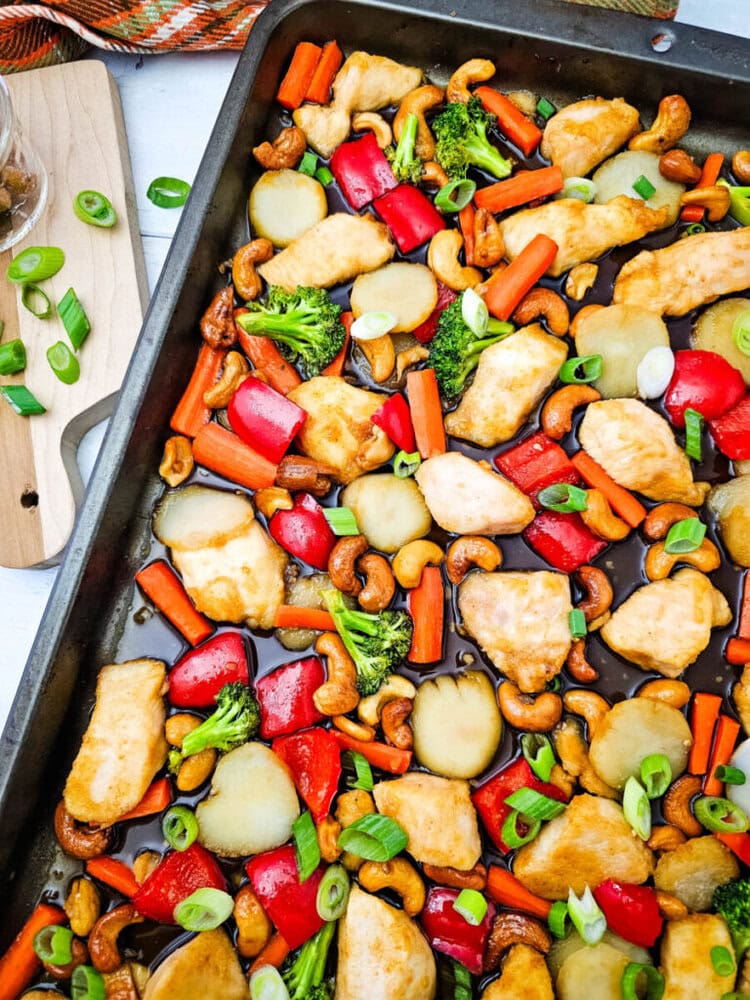 Sheet pan cashew chicken stir-fry with vegetables and cashews garnished with green onions