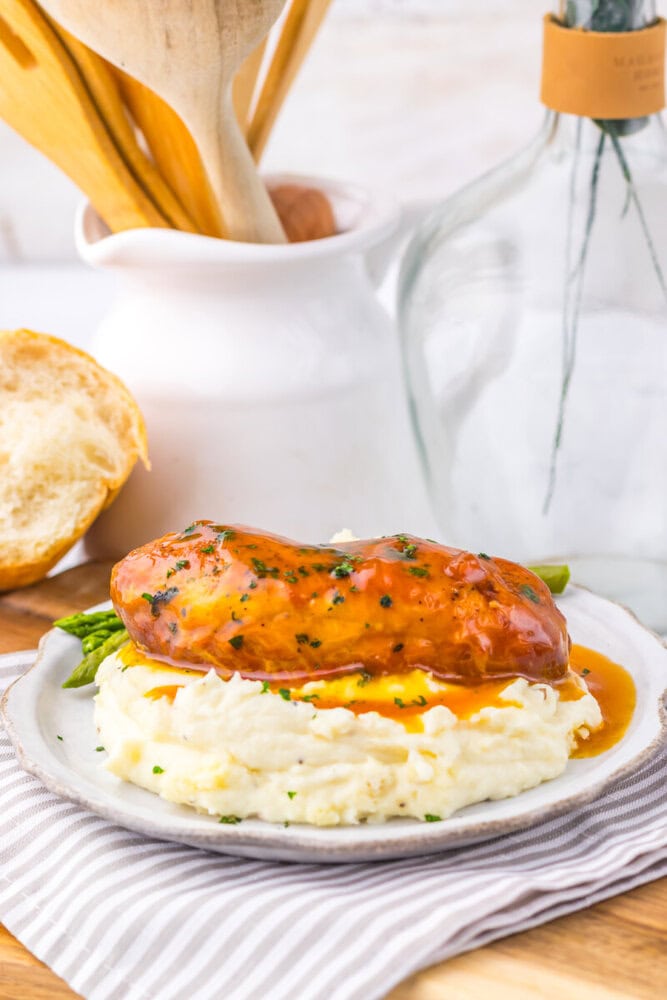 Slow cooker apricot brown sugar glazed chicken breast plated with mashed potatoes and asparagus
