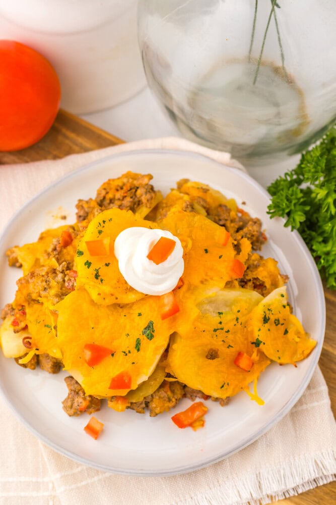Slow Cooker Cheesy Taco Potato Casserole plated with sour cream and fresh herbs