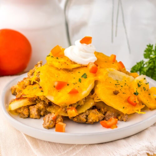 Slow cooker cheesy taco potato casserole plated with sour cream topping and fresh garnish