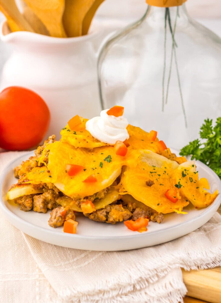 Slow cooker cheesy taco potato casserole plated with sour cream and peppers