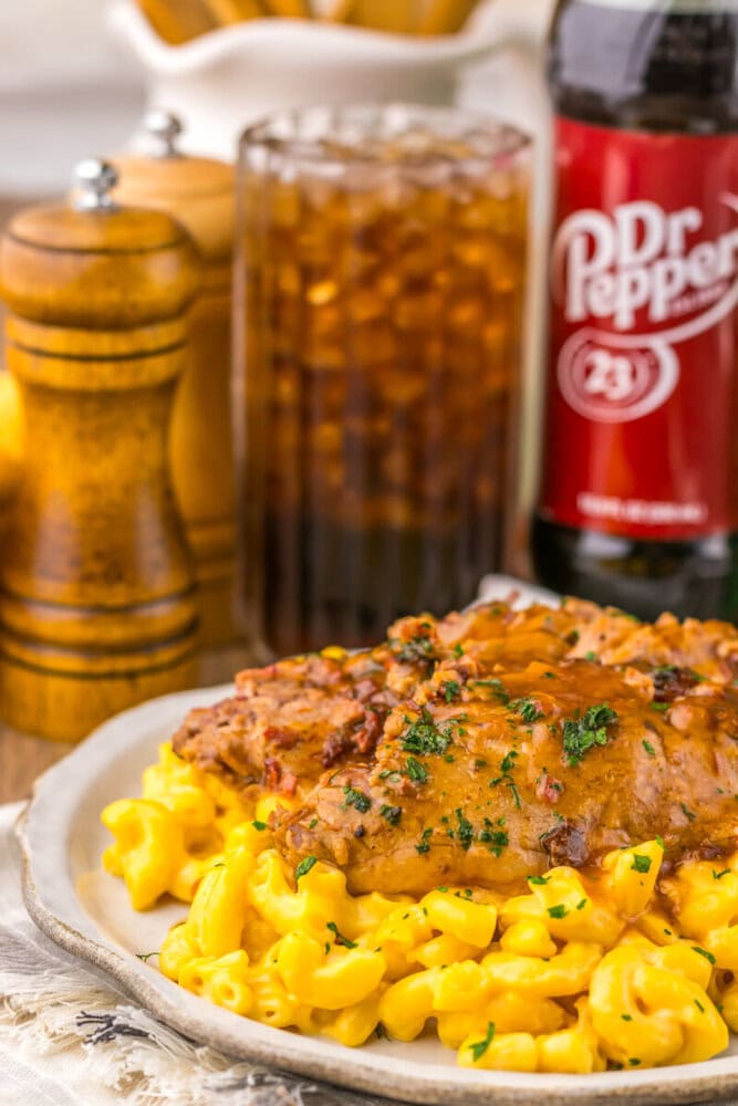 Slow cooker Dr Pepper BBQ brisket plated with corn and garnished with parsley, served with Dr Pepper and condiments