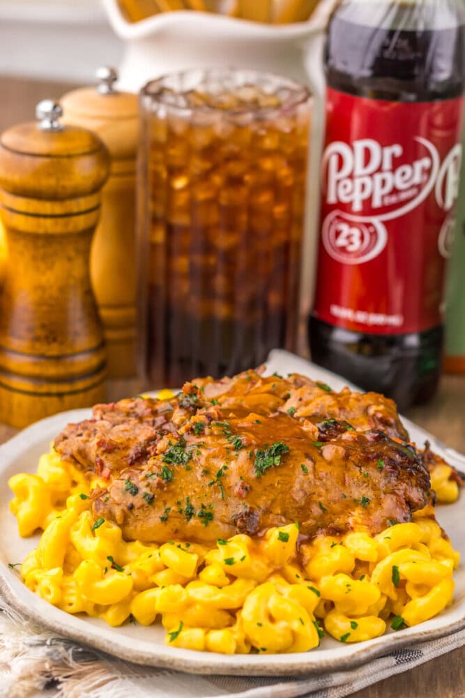 Slow cooker Dr Pepper BBQ brisket with mac and cheese, garnished with parsley, served on white plate with Dr Pepper bottle in background