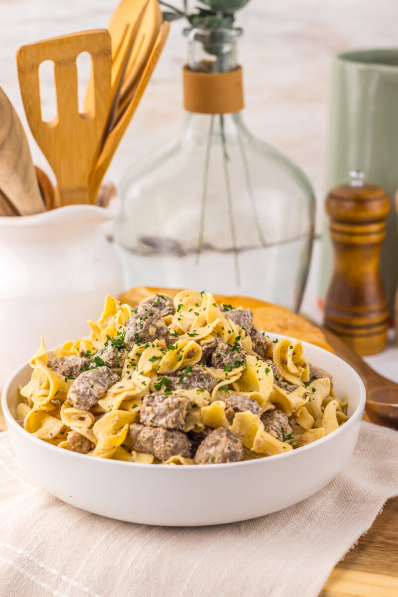 Slow cooker garlic butter beef and noodles in white bowl garnished with parsley, ready to serve