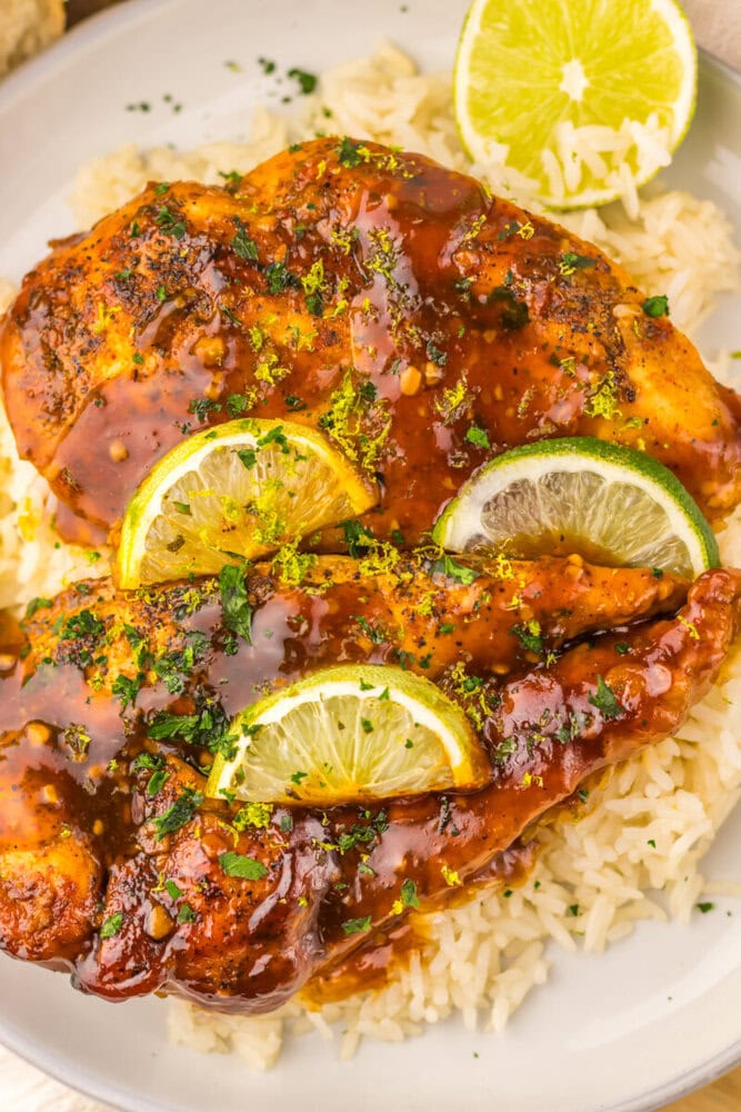 Slow cooker honey lime chicken glazed with herbs and lemon slices served over pasta
