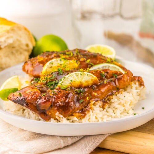 Slow cooker honey lime chicken glazed with caramelized coating served on white rice with lime garnish