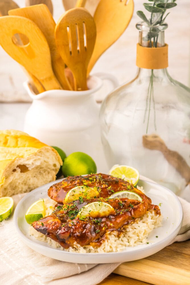 Slow cooker honey lime chicken glazed with lime slices served over rice on white plate