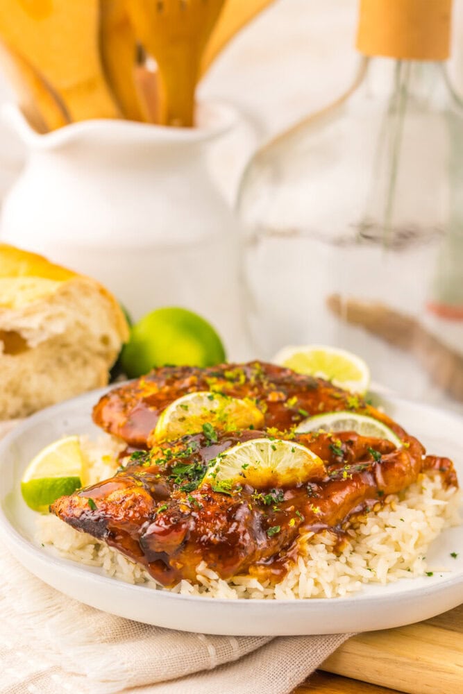 Slow cooker honey lime chicken with caramelized glaze served over rice with lime garnish