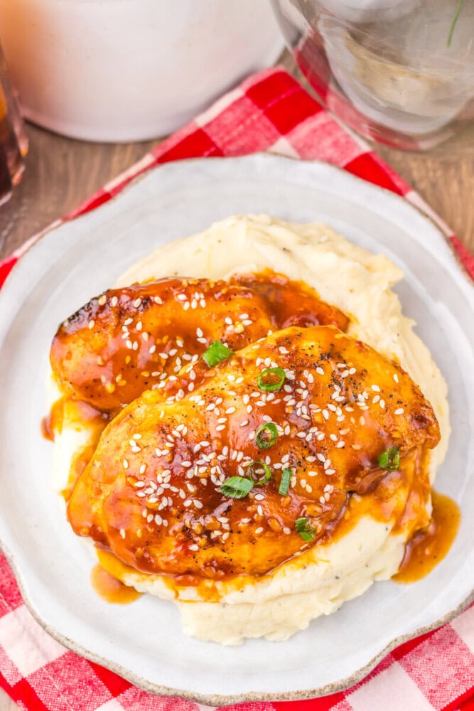 Slow cooker honey sesame chicken served over mashed potatoes with sesame seeds and green onion garnish